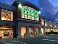 the entrance to a grocery store is lit up at dusk