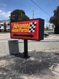 an advance auto parts sign on the side of the road