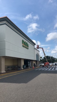 the exterior of a grocery store is being painted